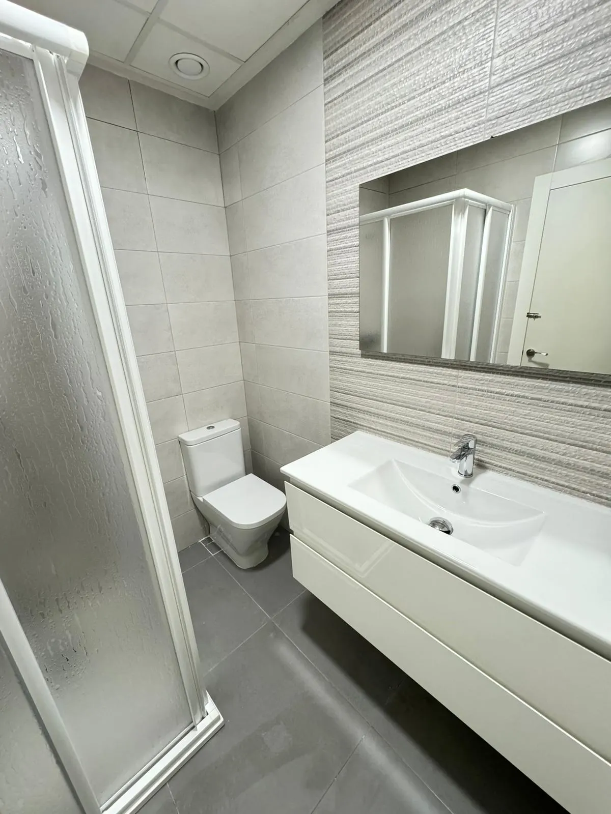 Baño reformado con ducha, lavabo y espejo en Greenhome Lepanto